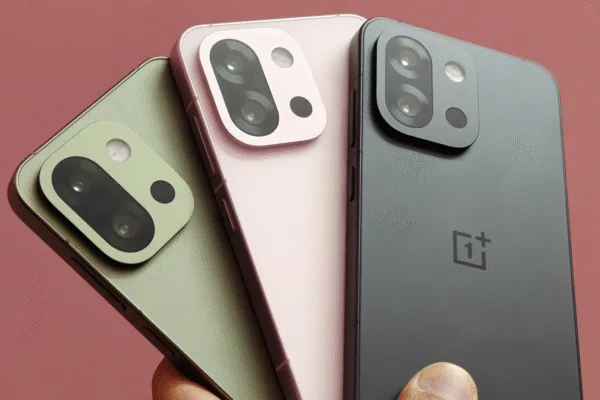 OnePlus 13s smartphones in black, pink, and green colors held in a hand against a pink background
