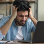 An Indian person sitting alone in a modern room, looking frustrated and stressed, representing modern life pressure and information overload.